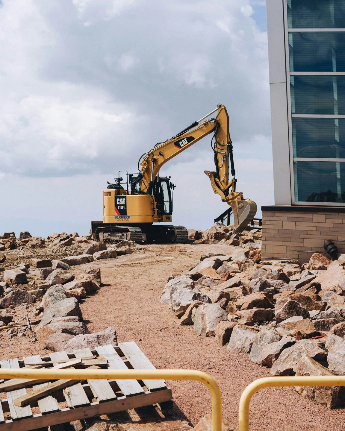 Excavator clearing rubble beside a building
