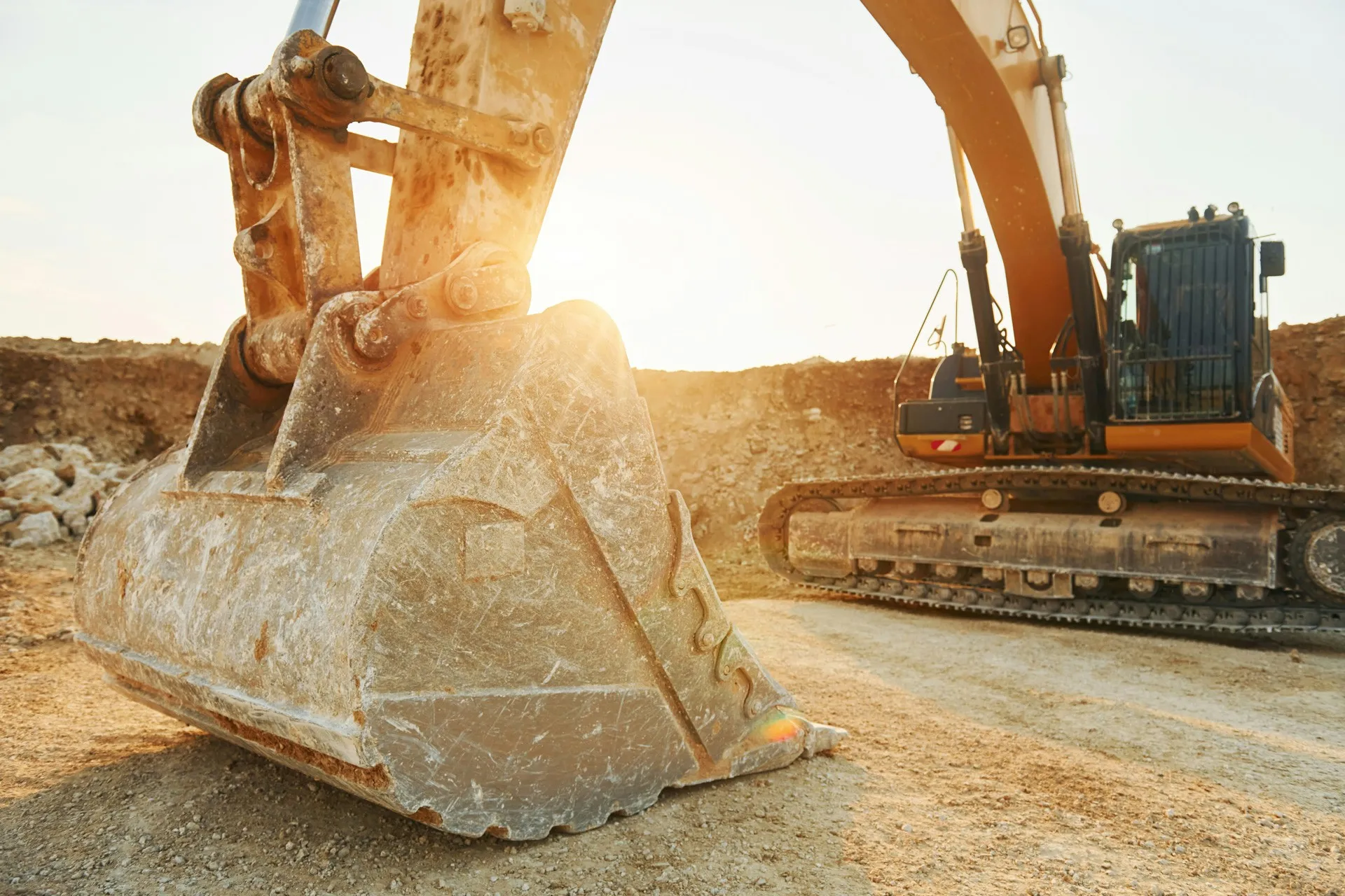 Excavator bucket resting on a quarry floor at sunset
